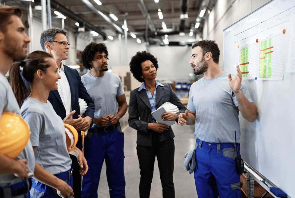 Groupe de personnes qui discutent devant un tableau blanc.